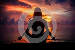 Woman meditating, relaxing in yoga pose at sunset, zen meditation