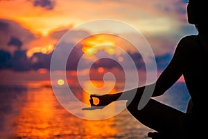 Woman meditating, relaxing in yoga pose at sunset, zen meditation