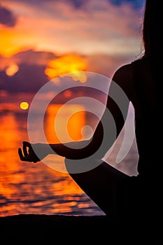 Woman meditating, relaxing in yoga pose at sunset, zen meditation