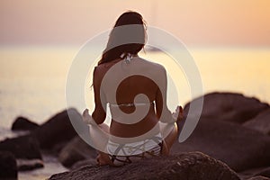 Woman meditating on sea beach