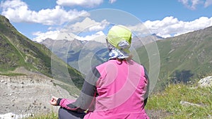 A woman meditating sitting high in the mountains. Nice view of Elbrus