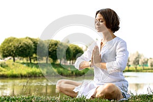 Woman meditating in sukhasana pose at the river-bank photo