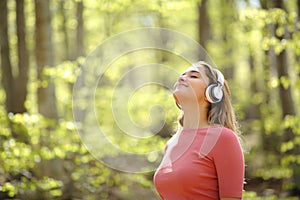 Woman meditating wearing headphones in a forest