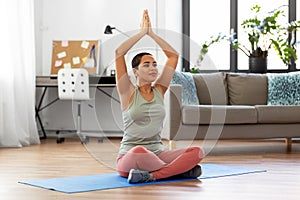 Woman meditating in yoga lotus pose at home