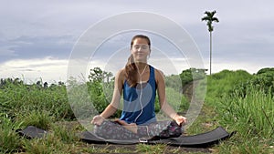 Woman meditating in yoga pose and listening to mantra on smartphone