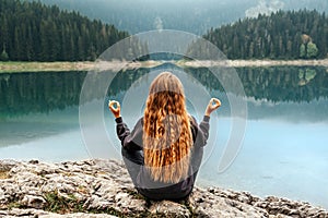 Woman Meditating in Yoga Pose by Mountain Lake