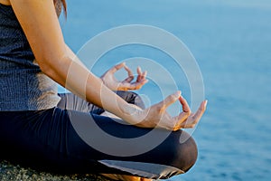 The woman meditating in a yoga pose on the tropical beach. Female meditating overlooking the beautiful sunrise. Healthy mind body