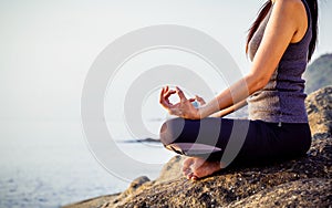 The woman meditating in a yoga pose on the tropical beach. Female meditating overlooking the beautiful sunrise. Healthy mind body