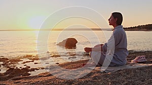 Woman meditating, zen yoga meditation practice breath exercise in nature. Yogi girl is sitting in sunset, healthy