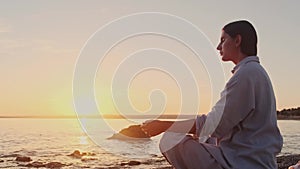 Woman meditating, zen yoga meditation practice breath exercise in nature. Yogi girl is sitting in sunset, healthy