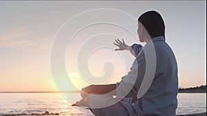 Woman meditating, zen yoga meditation practice breath exercise in nature. Yogi girl is sitting in sunset, healthy