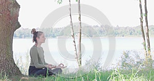 Woman meditating, zen yoga meditation practice in nature. Yogi girl is sitting in lotus pose, healthy lifestyle