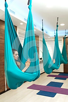 Woman meditation in hammock. fly yoga stretching exercises in gym. Fit and wellness lifestyle