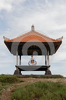A woman in a meditative yoga pose in a Balinese pavilion, creating a picture of tranquility and balance. Zen Balance photo