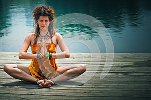 Woman in a meditative yoga position by lake