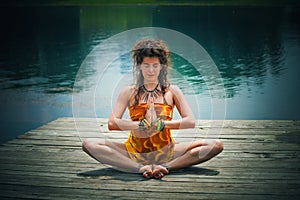 Woman in a meditative yoga position by the lake photo