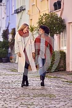 Woman Meeting Female Friend Walking Along Residential City Street In Fall Or Winter