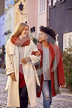 Woman Meeting Female Friend Walking Along Residential City Street In Fall Or Winter