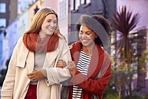 Woman Meeting Female Friend Walking Along Residential City Street In Fall Or Winter