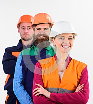 Woman and men in hard hats stand close as team.