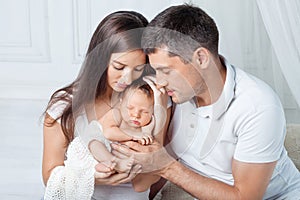 Woman and man holding a newborn. Mom, dad and baby. Close-up. Portrait of  smiling family with newborn on the hands. Happy family