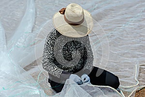 Woman mending fishing nets