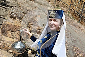 Woman with metal jug in Karachay clothes
