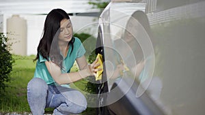 Woman with microfiber cloth cleaning car wheel