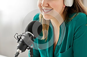 Woman with microphone recording podcast at studio photo