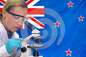 Woman with a microscope against New Zealand flag background. Medical technology and pharmaceutical research in New Zealand