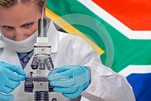 Woman with a microscope against South Africa flag background. Medical technology and pharmaceutical research in South Africa