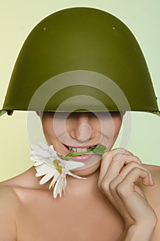 Woman in a military helmet bites chamomile
