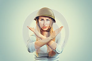 Woman in military helmet with crossed arms gestures stop, no
