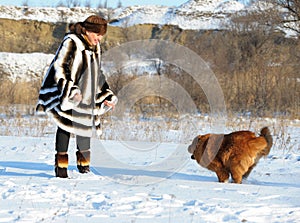 The woman in a mink fur coat plays with a dog