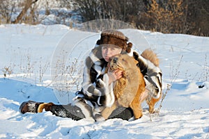 The woman in a mink fur coat plays with a dog