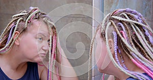 Woman mirror bathroom bright colored afro braids fixing hair morning routine