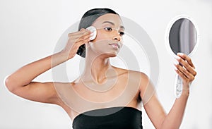 Woman, mirror and cotton pad for face, cosmetics and aesthetic skincare in studio on white background. Indian female