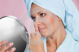 Woman with mirror touching her nose