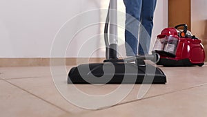 woman mistress in the house vacuums the tile floor