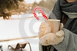 Woman in mittens hold cup of hot drink outdoor in winter