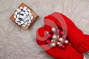 Woman in mittens holding Christmas balls and gift box