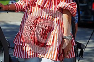 Woman with Miu Miu red leather bag, white and red striped shirt and Rolex Submariner watch