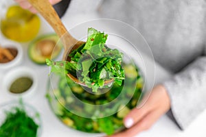 Woman mix salad of fresh green vegetables and herbs. Raw food concept. Vegan menu. Cooking healthy diet or vegetarian