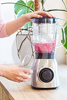 A woman mixes a delicious almond milk and berry smoothie in a blender. Smoothie diet.