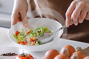 Woman mixes vegetable salad in bowl. Home cooking for a healthy diet