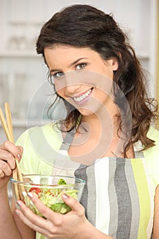 Woman mixing bowl of salad leaves