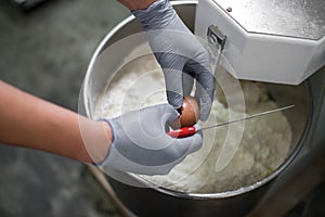 Woman mixing dough with professional kneader machine at the manufacturing