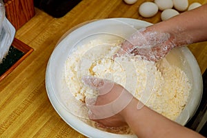Woman mixing flour and cheese for making cheese bread dough