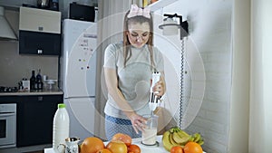 Woman mixing fruit cocktail using blender in kitchen