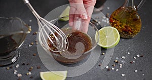 Woman mixing teriyaki say sauce and olive oil with whisk in a glass bowl preparing marinade